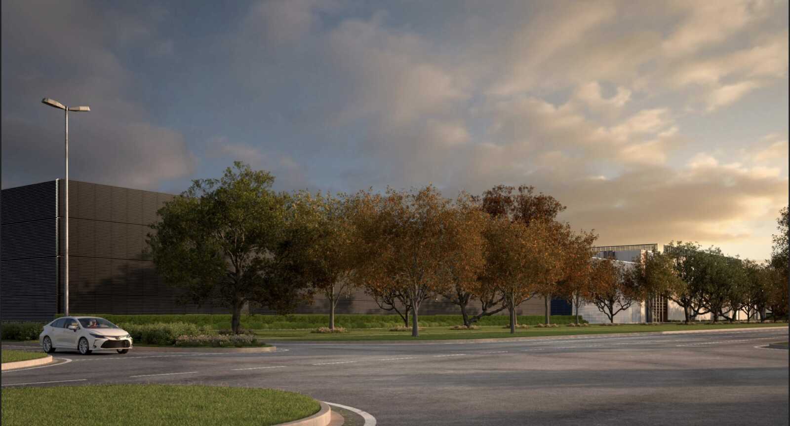 White car parked on a curved road in a corporate parking lot with trees and a modern building in the background at sunset
